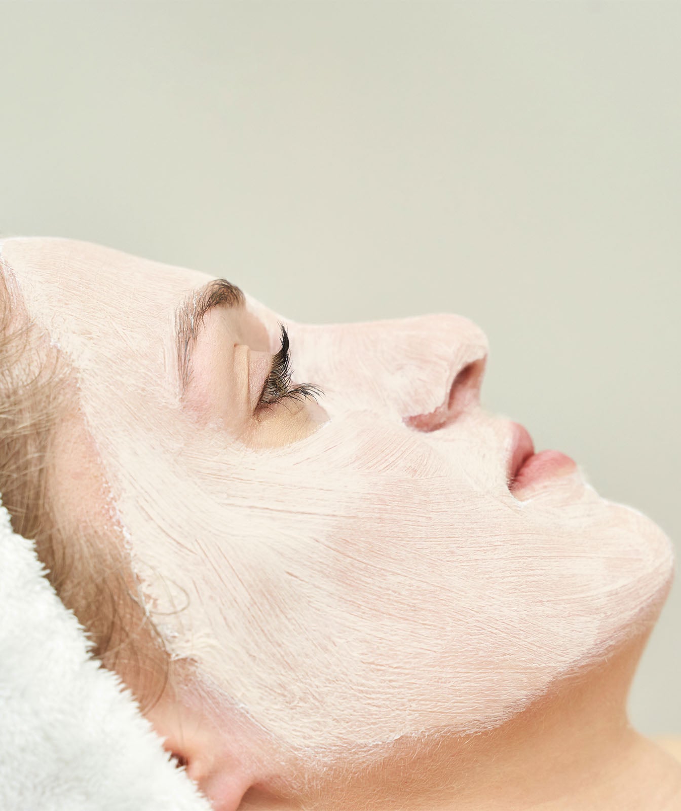 Imagen relajante de una mujer recostada con los ojos abiertos, luciendo una capa uniforme de la &