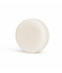 Champú sólido fortificante anticaída de color blanco, presentado sobre una superficie blanca.