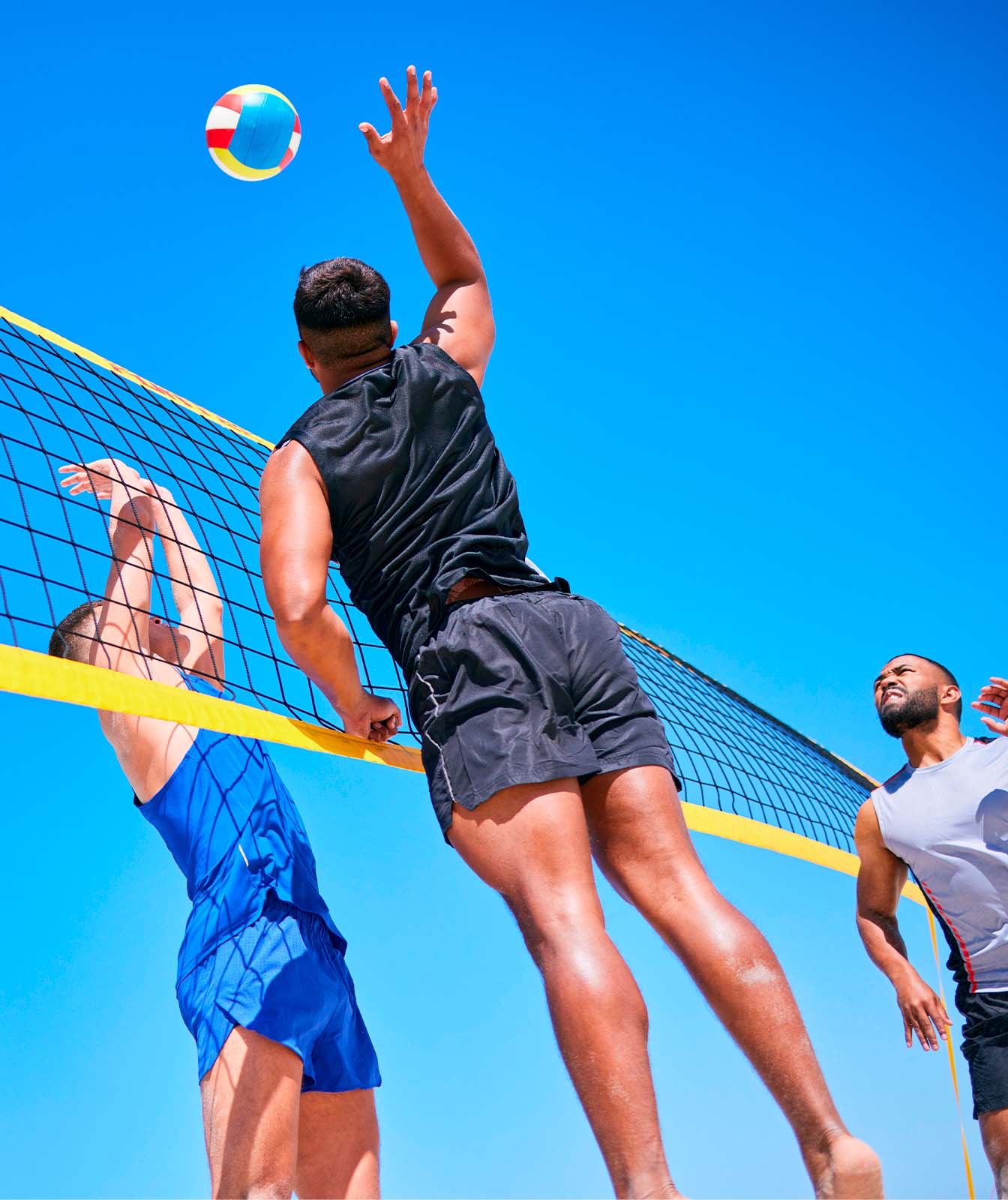 Jugadores de vóley playa en acción bajo un cielo azul despejado, ilustrando el ambiente activo y al aire libre para el cual el protector solar deportivo &