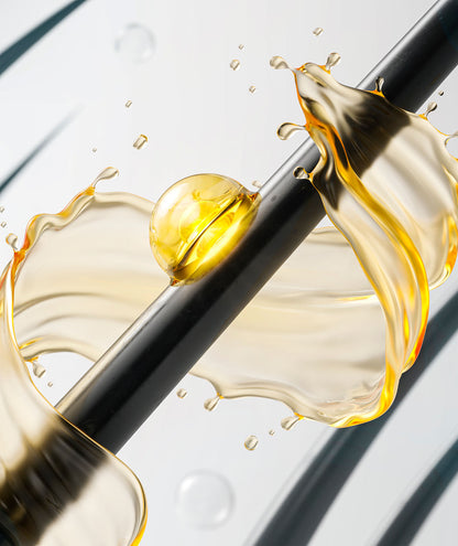 Imagen dinámica de una gota de aceite de tratamiento capilar suspendida en el aire, con salpicaduras doradas y ámbar que resaltan su textura rica y nutritiva. Este aceite es parte de la línea &